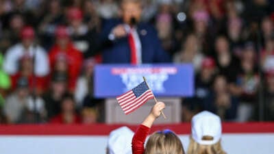 A child holds a small American flag as Republican presidential candidate and former President Donald Trump speaks during a campaign rally at the Ryder Center for Health and Physical Education at Saginaw Valley State University in Saginaw, Michigan, on October 3, 2024.