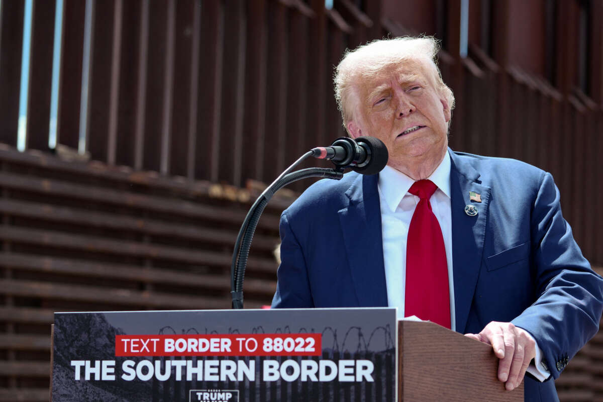 Donald Trump grimaces at a podium by his border wall