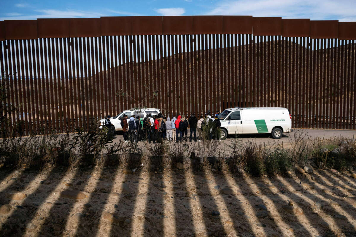 Border patrol agents talk to a group of migrant people, mostly from African countries, before processing them after crossing the U.S.-Mexico border, taken from Tijuana, Baja California state, Mexico, on November 11, 2022.