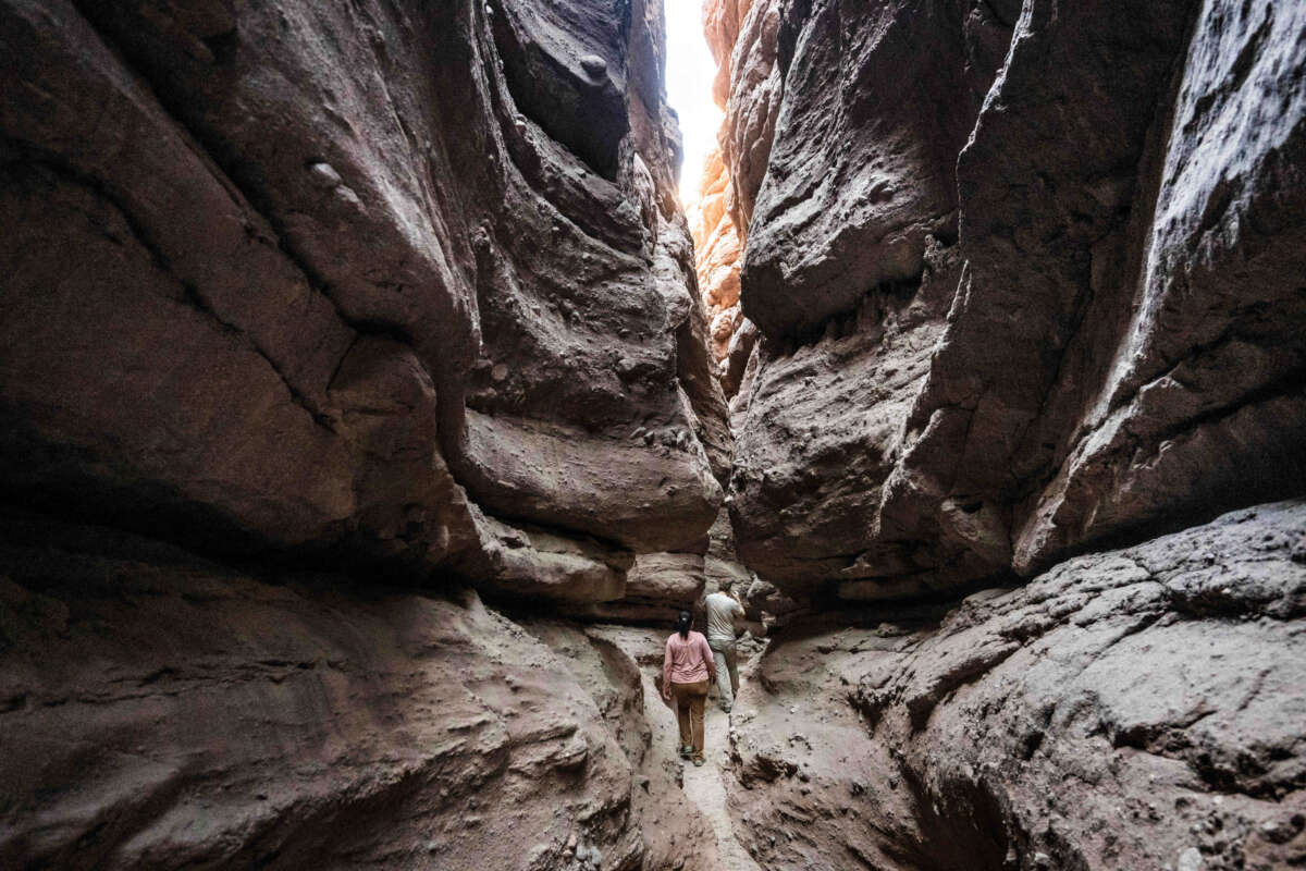 Sendy Hernández Orellana Barrows, conservation program manager for the Council of Mexican Federations (COFEM), and Colin Barrows, a member of the CactusToCloud Institute, hike through a slot canyon in the the Ladder Canyon trail at Painted Canyon located in the Mecca Hills Wilderness near Mecca on October 13, 2022. Local organizations are working together to establish a new national monument in the Chuckwalla Valley, south of Joshua Tree National Park. The proposed Chuckwalla National Monument would protect important historical lands, cultural resources and biodiverse species.