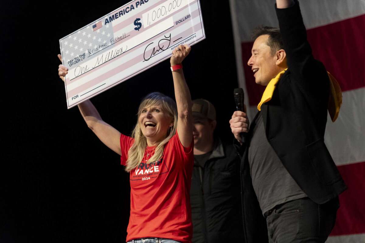 Elon Musk awards Kristine Fishell with a $1 million check during the town hall at the Roxain Theater on October 20, 2024, in Pittsburgh, Pennsylvania.