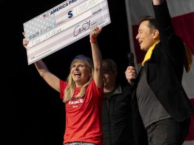 Elon Musk awards Kristine Fishell with a $1 million check during the town hall at the Roxain Theater on October 20, 2024, in Pittsburgh, Pennsylvania.