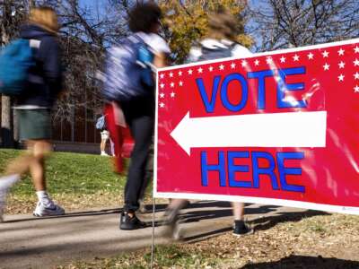 Students walk past a voting sign outside a polling location on November 8, 2022, in Denver, Colorado.