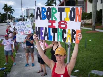 People hold up signs during a pro-abortion rights rally on the second anniversary of the Supreme Court ruling to overturn Roe v. Wade, in West Palm Beach, Florida, on June 24, 2024.