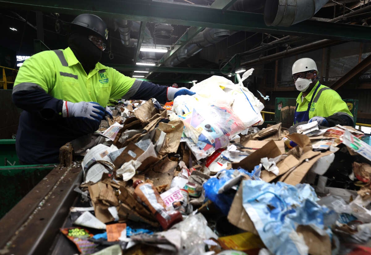 Workers pull plastic bags off of a conveyor belt as they sort through recyclable materials at Recology's Recycle Central on September 24, 2024, in San Francisco, California.