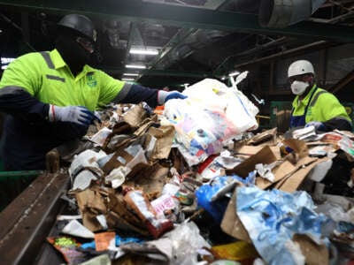 Workers pull plastic bags off of a conveyor belt as they sort through recyclable materials at Recology's Recycle Central on September 24, 2024, in San Francisco, California.