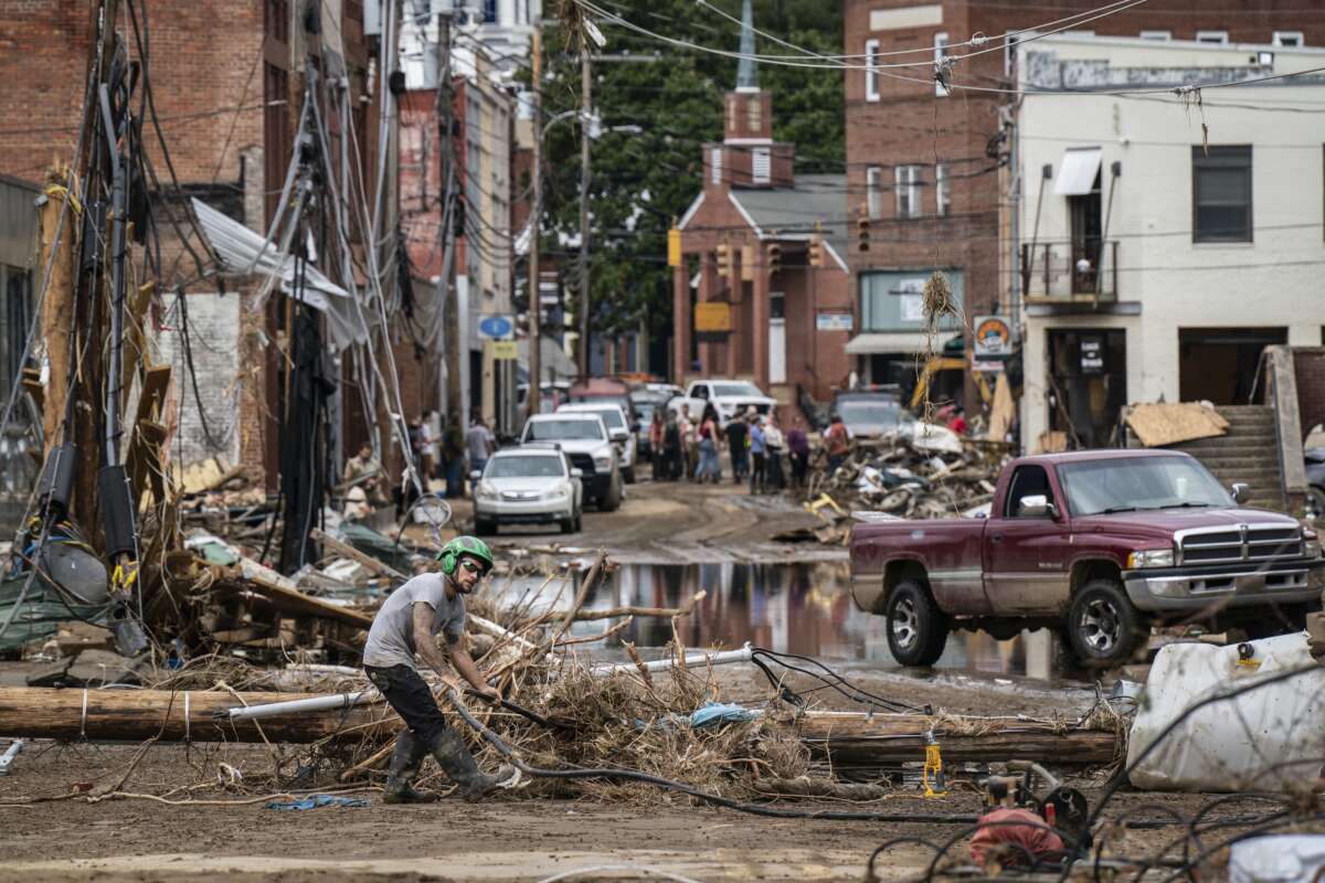 Workers, community members and business owners clean up debris in the aftermath of Hurricane Helene in Marshall, North Carolina, on September 30, 2024.