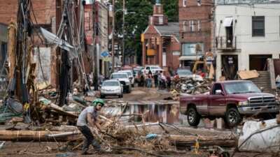 Workers, community members and business owners clean up debris in the aftermath of Hurricane Helene in Marshall, North Carolina, on September 30, 2024.