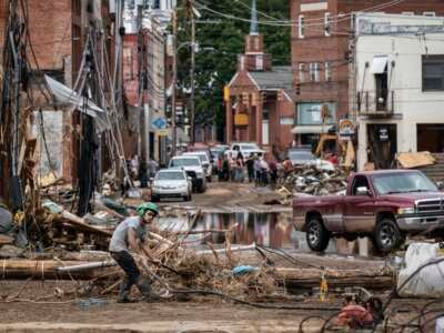 Workers, community members and business owners clean up debris in the aftermath of Hurricane Helene in Marshall, North Carolina, on September 30, 2024.