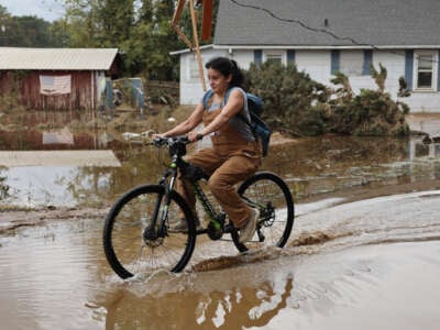 A person bicycles through floodwaters remaining from Hurricane Helene on October 4, 2024, in Swannanoa, North Carolina.