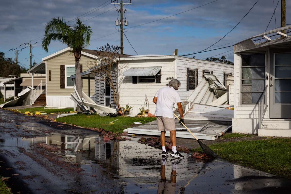 A resident cleans the front of his mobile home after Hurricane Milton's landfall on October 10, 2024, in Sarasota, Florida.