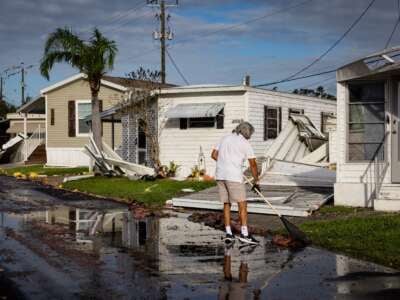 A resident cleans the front of his mobile home after Hurricane Milton's landfall on October 10, 2024, in Sarasota, Florida.