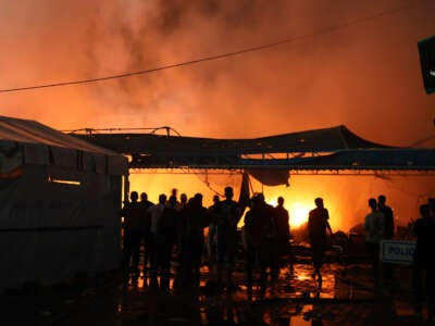 People attempt to extinguish a fire following an Israeli strike on tents sheltering displaced people in Deir el-Balah, Gaza, on October 14, 2024.