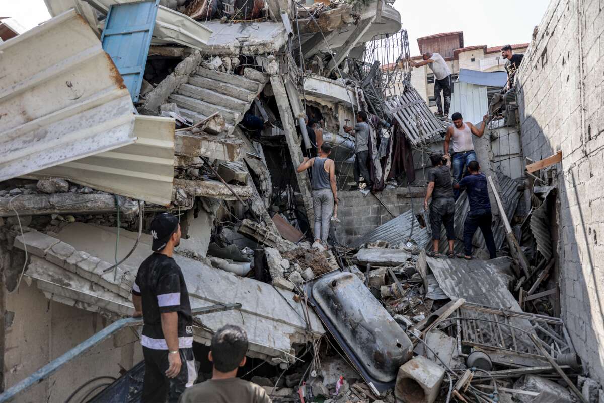 People gather outside a collapsed building as they attempt to extricate a man from underneath the rubble following Israeli bombardment in the Saftawi district in Jabalia in the northern Gaza Strip on October 15, 2024.