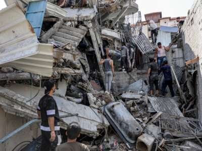 People gather outside a collapsed building as they attempt to extricate a man from underneath the rubble following Israeli bombardment in the Saftawi district in Jabalia in the northern Gaza Strip on October 15, 2024.