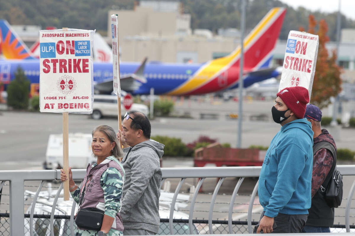 People carry Boeing strike signs as they walk past parked Boeing 737 planes near Boeing Field following a strike rally for the International Association of Machinists and Aerospace Workers at the Seattle Union Hall in Seattle, Washington, on October 15, 2024.