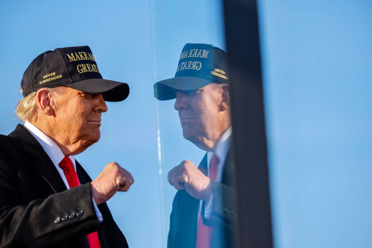 Donald Trump poses in front of bulletproof glass