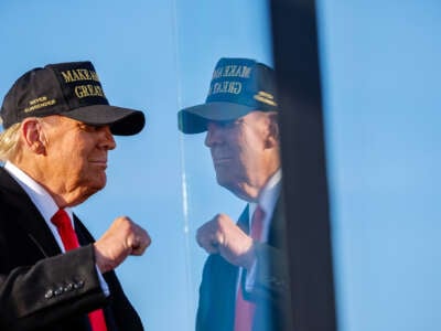 Donald Trump poses in front of bulletproof glass