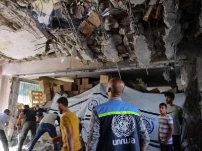 A United Nations Relief and Works Agency for Palestine Refugees (UNRWA) worker and displaced Palestinians check the damage inside a UN school-turned-refuge in the Al-Shati refugee camp near Gaza City in the northern Gaza Strip, following a reported Israeli strike on October 19, 2024.