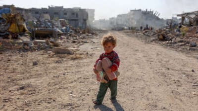 A displaced Palestinian child fleeing Beit Lahia in the northern Gaza Strip, walks on Gaza's main Salah al-Din road on the outskirts of Gaza City, on November 5, 2024.