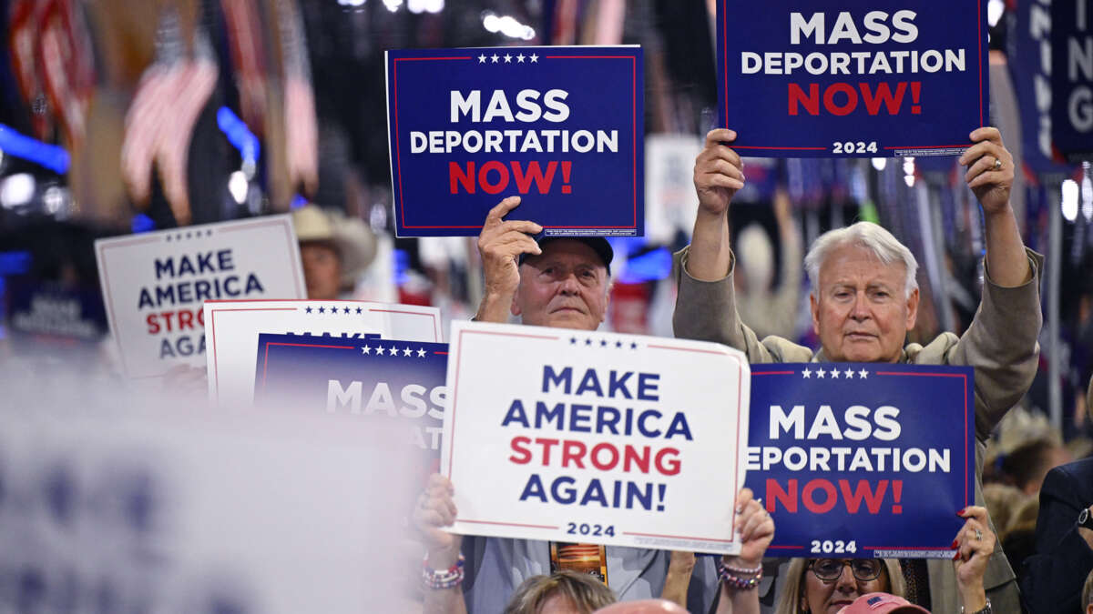 People hold signs reading "MASS DEPORTATIONS NOW" during a trump rally