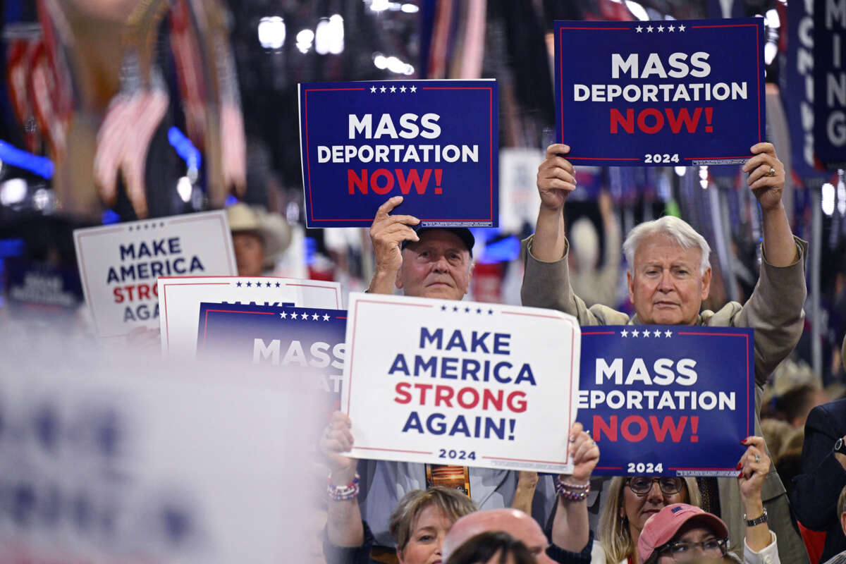 People hold signs reading "MASS DEPORTATIONS NOW" during a trump rally