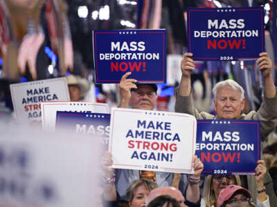 People hold signs reading "MASS DEPORTATIONS NOW" during a trump rally