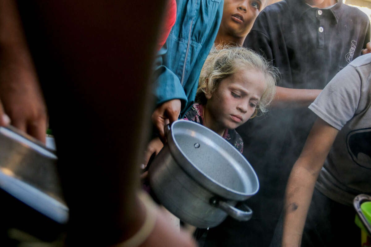 Displaced Palestinians queue to receive food rations, offered by a charity, in Gaza's Al-Shati refugee camp on October 17, 2024.