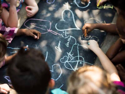 Kindergarten kids draw with chalk on blackboard