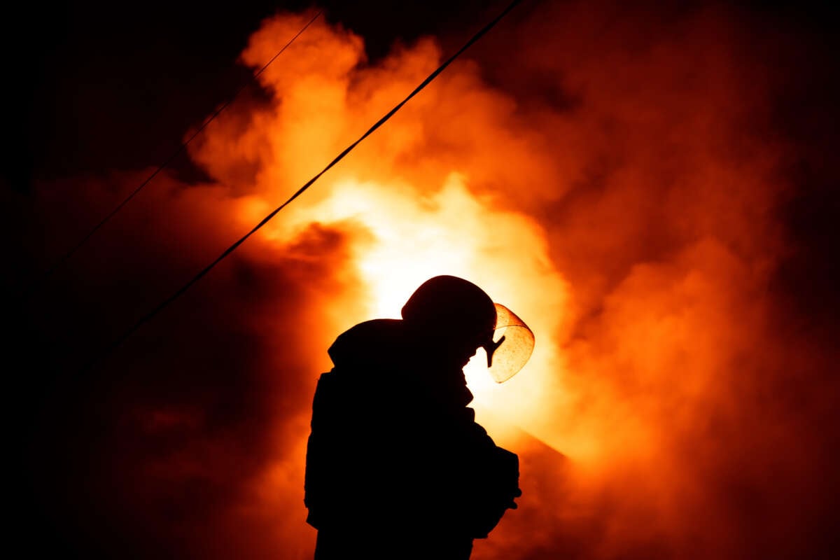 A firefighter stands in front of a fire