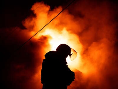 A firefighter stands in front of a fire