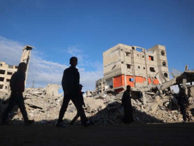 Palestinians walk past destruction following months of Israeli bombardment in the southern Gaza Strip city of Khan Yunis on November 19, 2024.