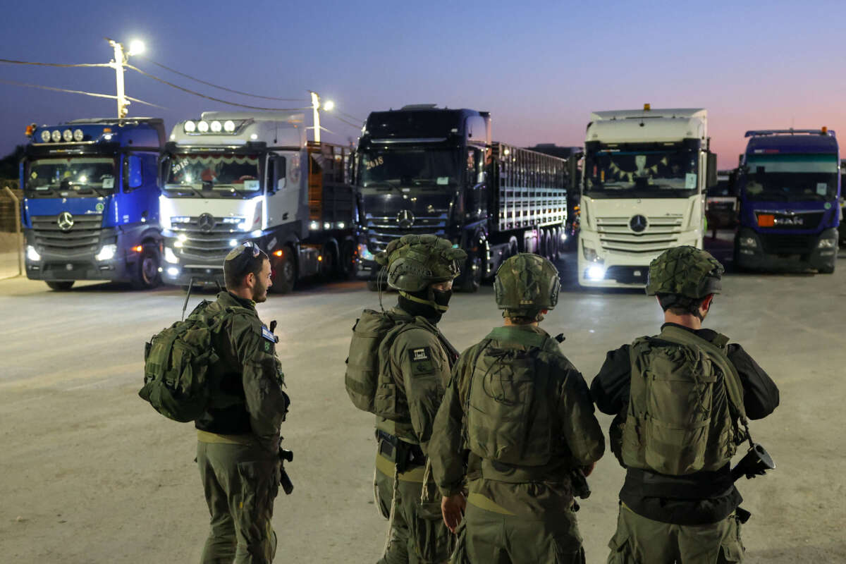 Israeli soldiers stand guard as trucks loaded with humanitarian aid delivered from Jordan wait to cross into Gaza on the border between Israel and the northern Gaza Strip, through the Israeli-controlled Erez crossing on October 21, 2024. (Photo taken during a controlled tour by the Israeli military.)