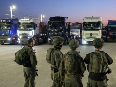 Israeli soldiers stand guard as trucks loaded with humanitarian aid delivered from Jordan wait to cross into Gaza on the border between Israel and the northern Gaza Strip, through the Israeli-controlled Erez crossing on October 21, 2024. (Photo taken during a controlled tour by the Israeli military.)