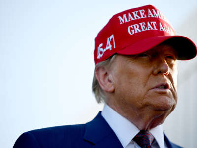 Donald Trump grimaces into the distance while wearing a red "Make America Great Again" hat