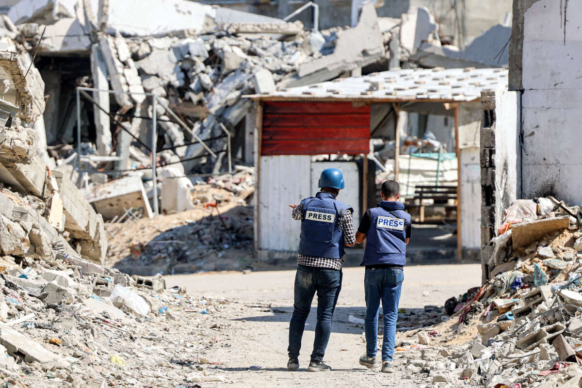 Journalists film while standing before destroyed buildings in the Jabalia camp for Palestinian refugees in the northern Gaza Strip on October 9, 2024.