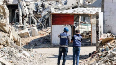 Journalists film while standing before destroyed buildings in the Jabalia camp for Palestinian refugees in the northern Gaza Strip on October 9, 2024.