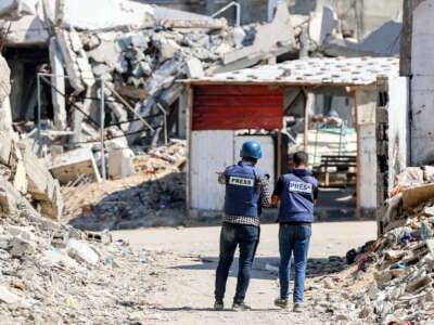 Journalists film while standing before destroyed buildings in the Jabalia camp for Palestinian refugees in the northern Gaza Strip on October 9, 2024.