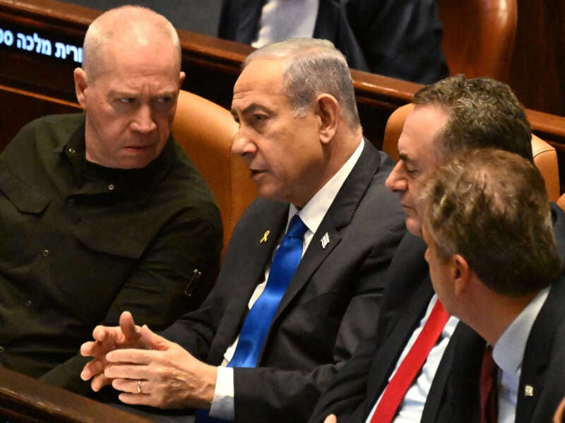 Israeli Prime Minister Benjamin Netanyahu (center) speaks to Defence Minister Yoav Gallant (left) at the opening of the 25th Parliament session in Jerusalem on October 28, 2024.