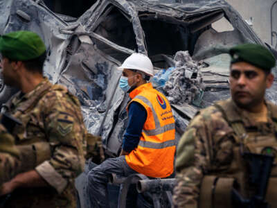 First responders take a moment of rest amid the rubble of buildings destroyed by Israeli forces