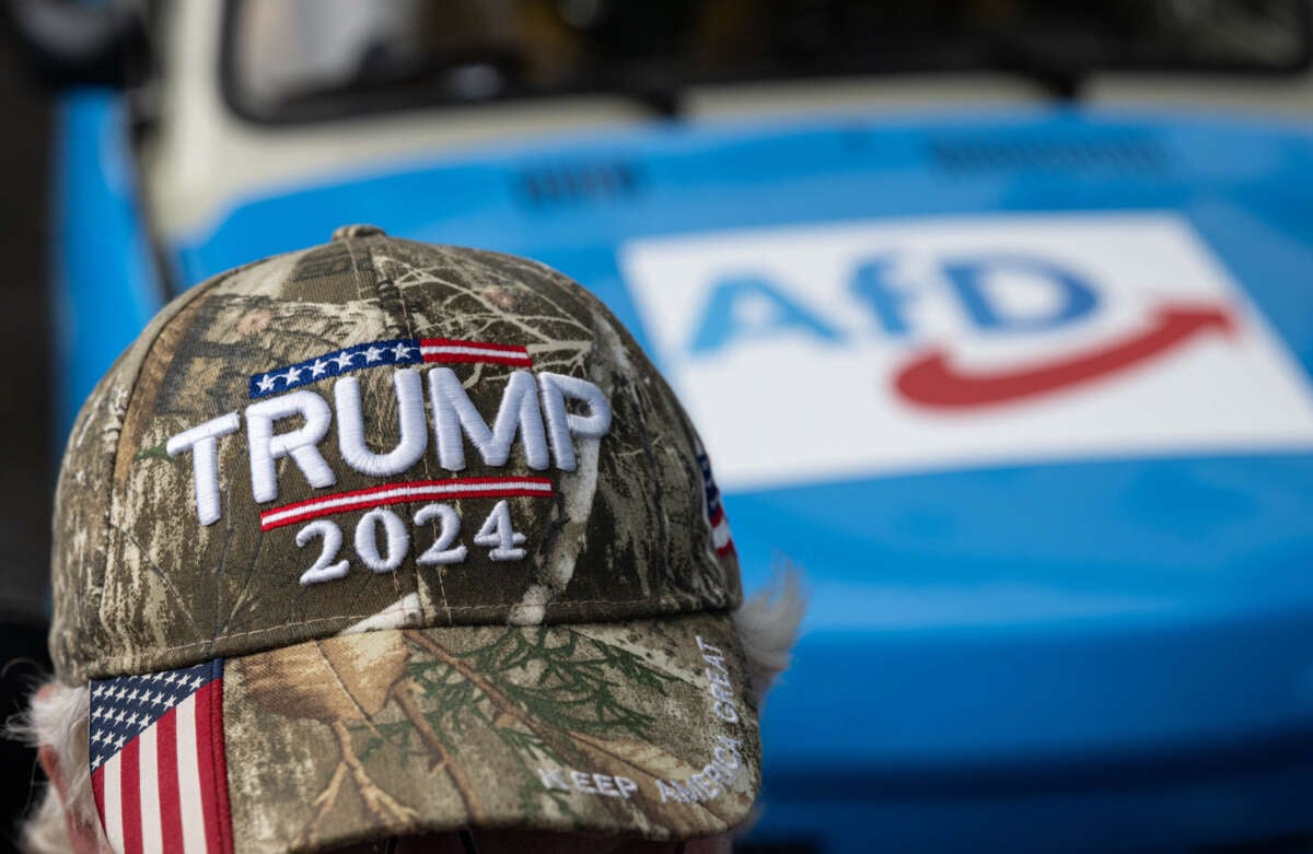 A campaign event participant wears a cap with the words Trump 2024 while sitting in front of a car with an AfD print on August 8, 2024, in Thuringia, Bad Salzungen, Germany.