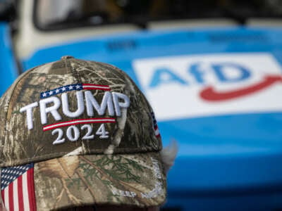 A campaign event participant wears a cap with the words Trump 2024 while sitting in front of a car with an AfD print on August 8, 2024, in Thuringia, Bad Salzungen, Germany.