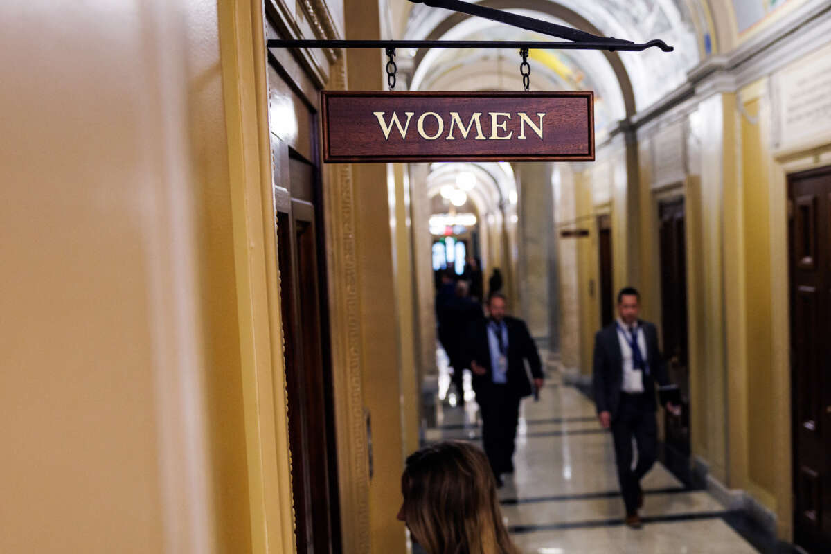 A woman enters a door labeled "WOMEN"