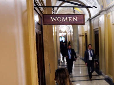 A woman enters a door labeled "WOMEN"