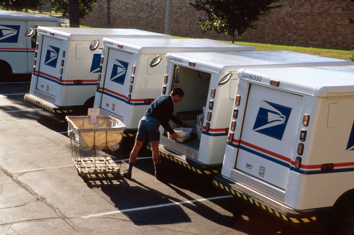 A mail carrier loads a truck.