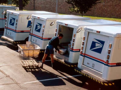 A mail carrier loads a truck.