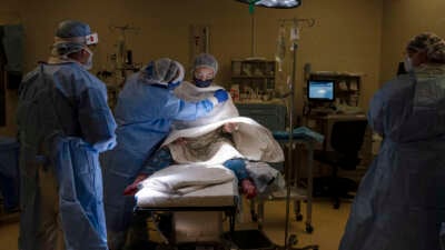 A young mother is supported by nurses as she is prepped by the anesthesiologist for an epidural before a cesarian section to deliver twins at the Women's Hospital at the the Doctors Hospital at Renaissance in McAllen, Texas, on July 7, 2020.