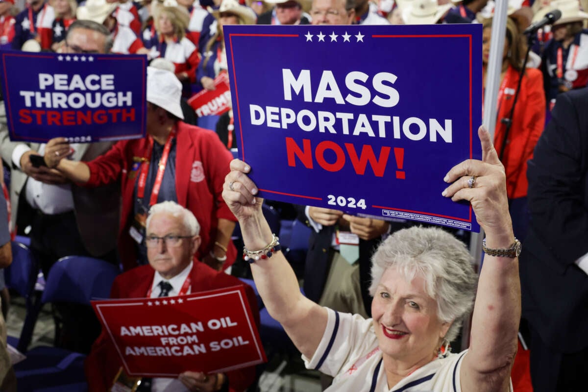 People hold signs that read "Mass Deportation Now!" on the third day of the Republican National Convention at the Fiserv Forum on July 17, 2024, in Milwaukee, Wisconsin.