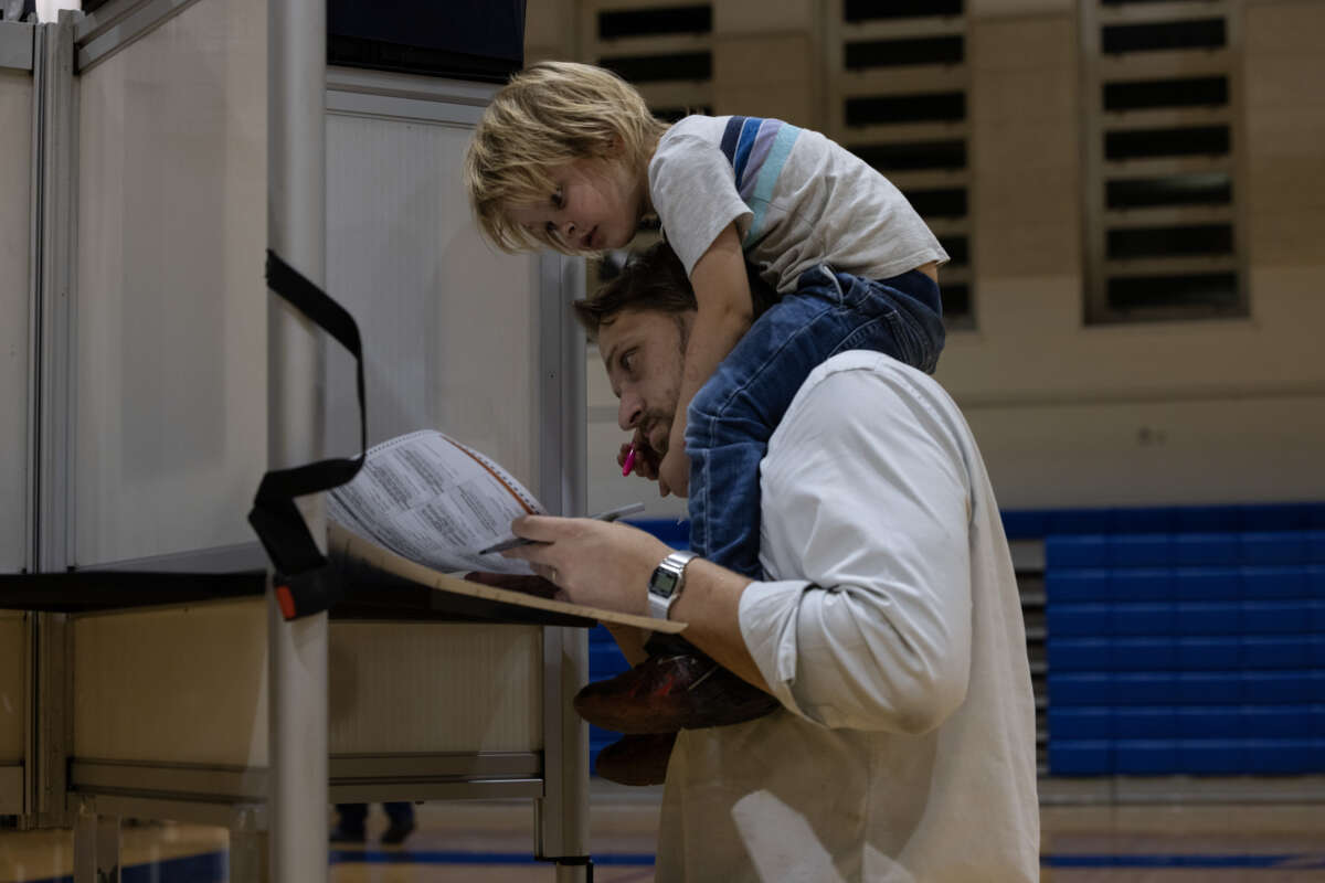 William Swanson votes carrying his son Oliver, 3, at a local polling station on November 5, 2024, in Washington, D.C.