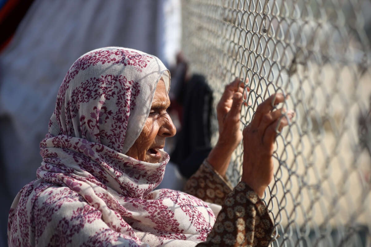 A displaced Palestinian woman looks through a fence in a tent camp in Khan Younis, southern Gaza Strip, on November 9, 2024.